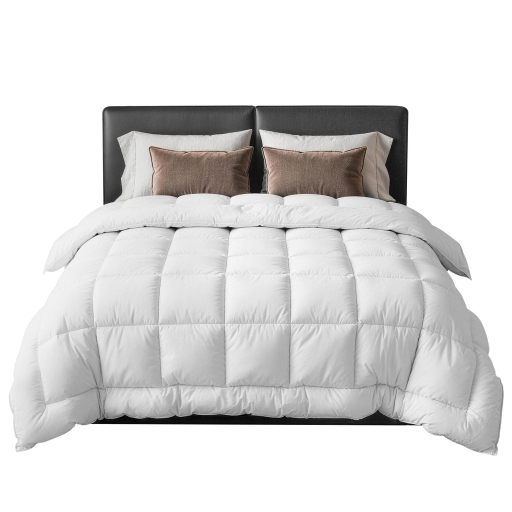 White comforter on a bed with brown pillows and headboard against a white background
