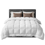 White comforter on a bed with brown pillows and headboard against a white background