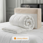 Folded white comforter with beige carrying bag on a bed