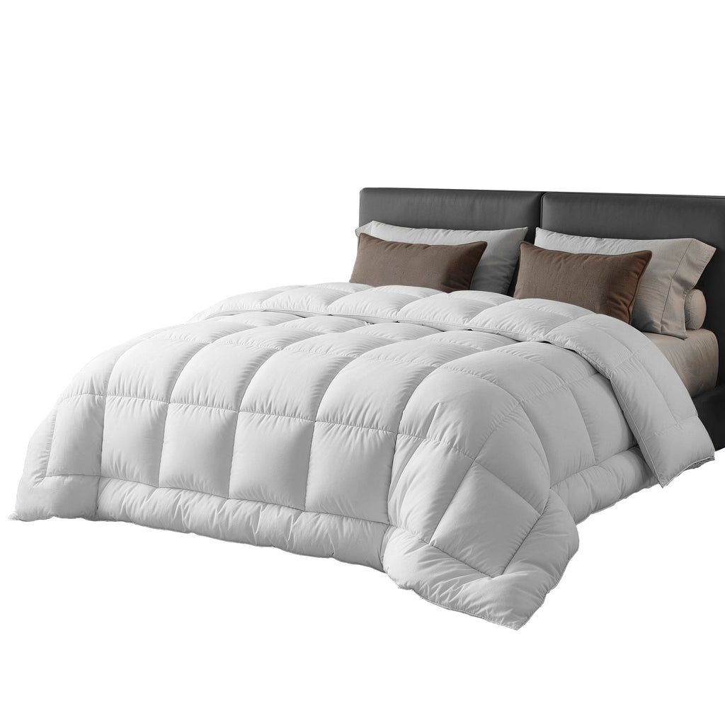 White comforter on a bed with brown pillows against a white background