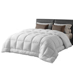 White comforter on a bed with brown pillows against a white background