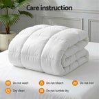 White comforter on a bed with care instructions displayed.