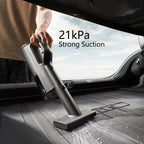 Person using a handheld vacuum cleaner in a car with '21kPa Strong Suction' text displayed.