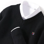 Black sweater with a small logo on a mannequin against a white background