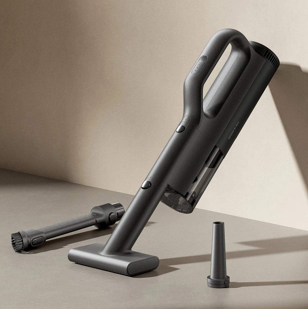 Black handheld vacuum cleaner with attachments on a beige background