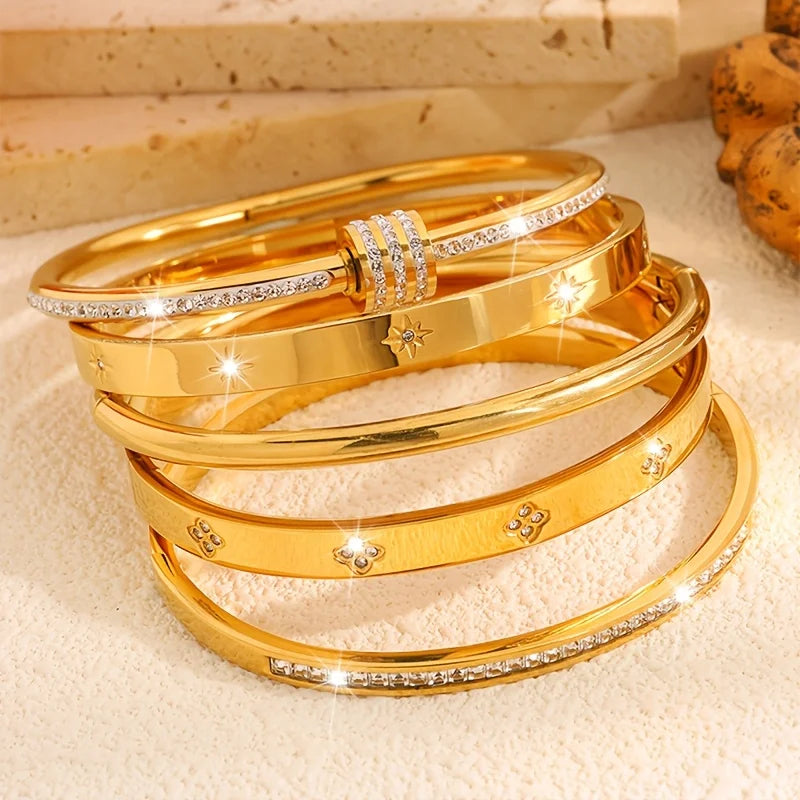 Stack of gold bracelets with diamond accents on a textured surface