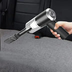 Hand holding a handheld vacuum cleaner cleaning a car seat.