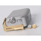 Small electronic device with gold and silver accents on a light gray background