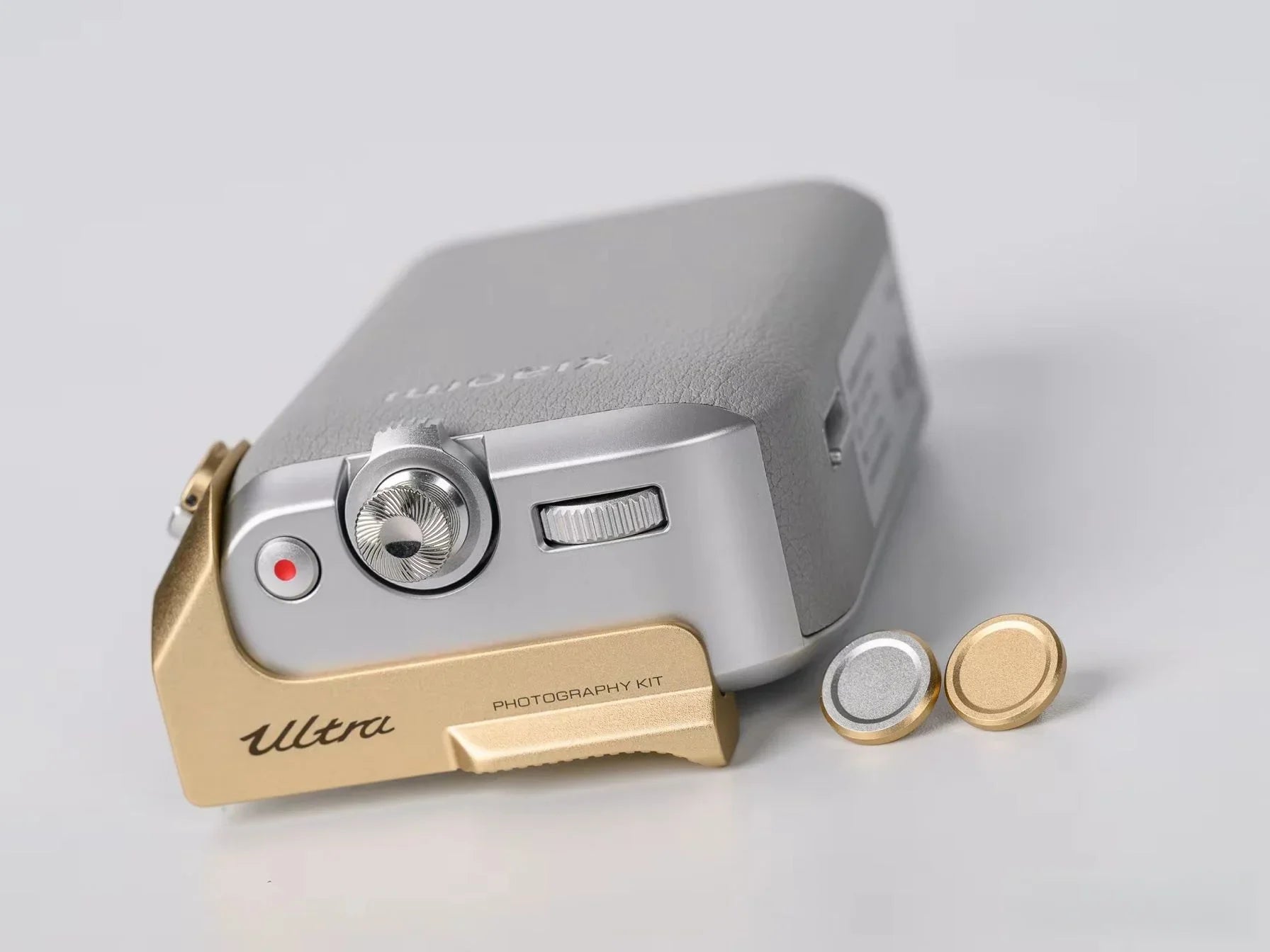 Camera with gold and silver attachments on a light gray background
