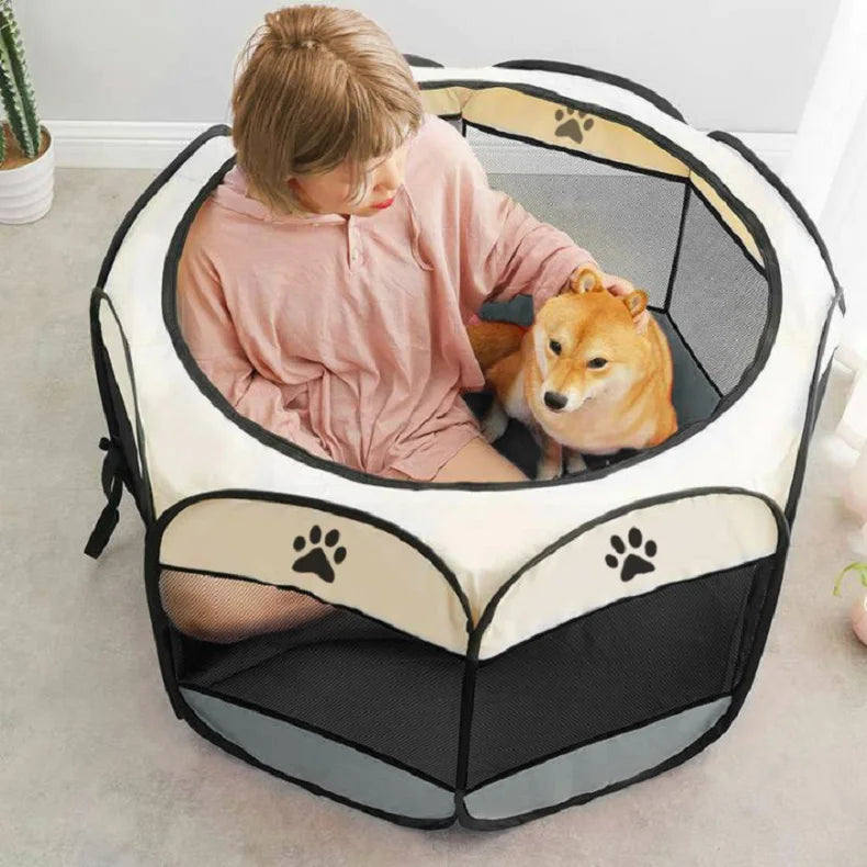 Person sitting with a dog inside a portable pet pen on a light-colored floor.