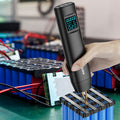 Hand holding a digital device over electronic components in a workshop setting