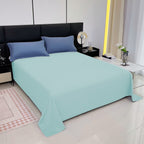 Bed with light blue bedding and dark blue pillows in a modern bedroom.