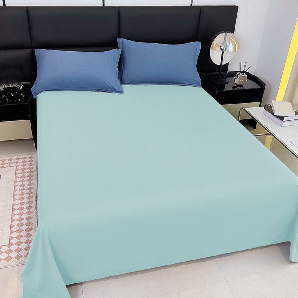 Bed with light blue fitted sheet and blue pillows in a bedroom setting.