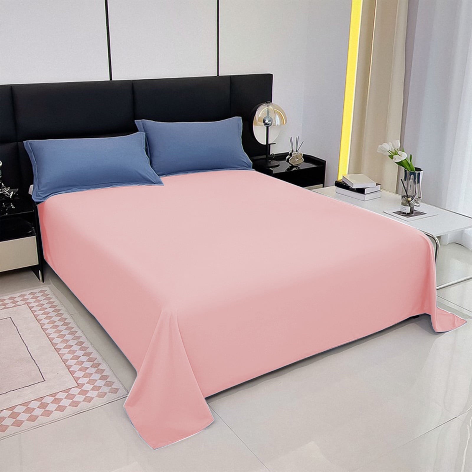 Bed with pink bedding and blue pillows in a modern bedroom setting.