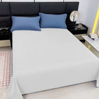 Bed with white fitted sheet and blue pillows in a bedroom setting.