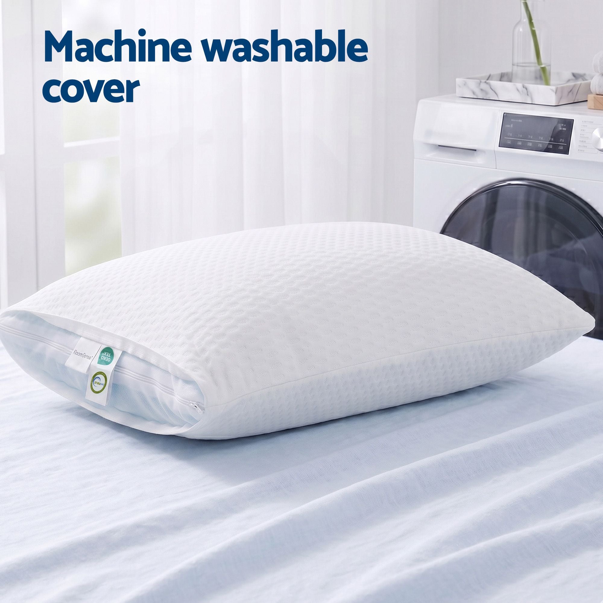 White pillow with machine washable cover on a bed next to a washing machine.